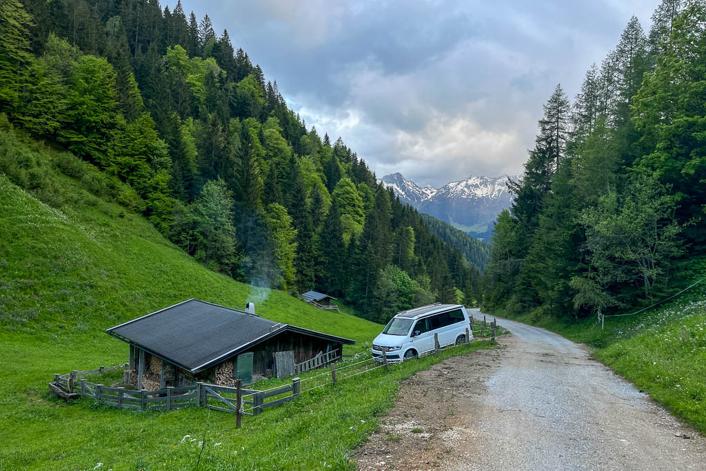 Ein VW Bulli am Wanderweg vor einer Holzhütte