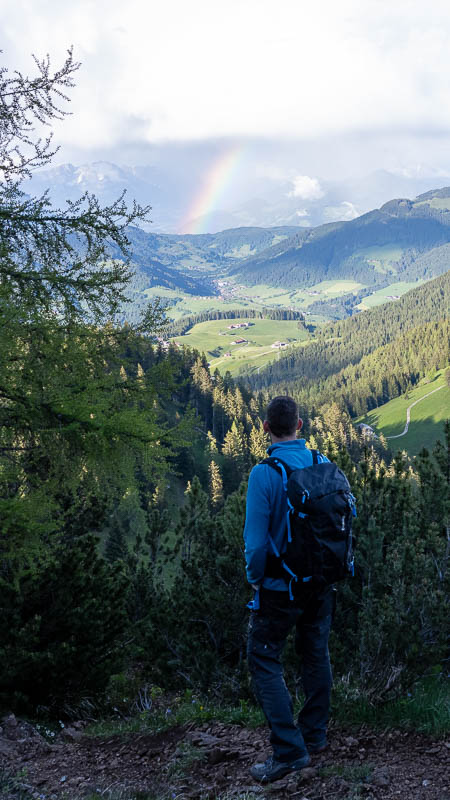 Ein Wanderer blickt zum Regenbogen über dem Alpbachtal