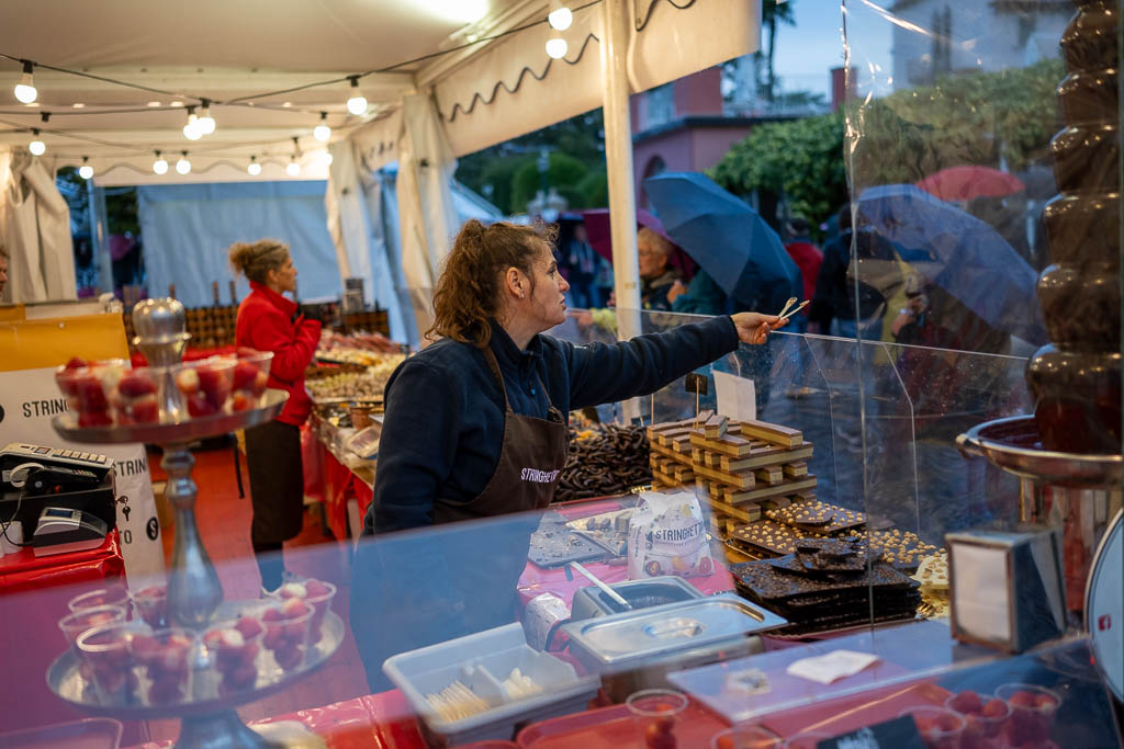 Eine Verkäuferin lässt Besucher vom Weinfest in Bardolino Schokolade probieren